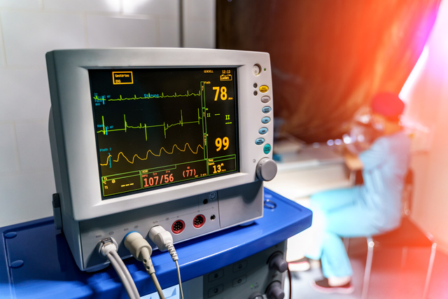 Modern medical monitor displaying statistics of patient. Medical worker working in quarantine.